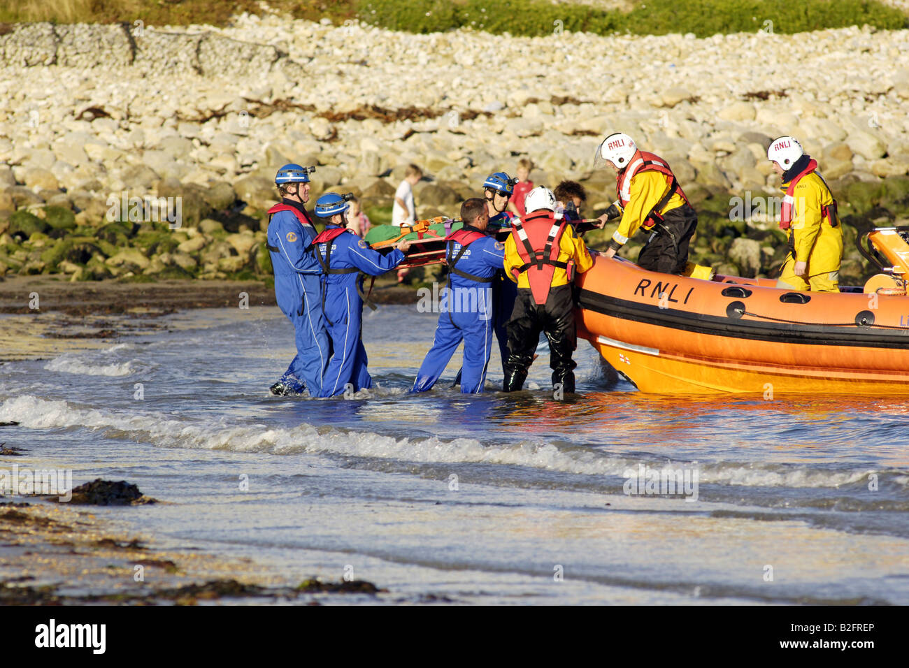 Küstenwache am Ufer Rettung Freiwilligen in seinem blauen Overalls heben einen Körper auf einem Rettungsboot warten Stockfoto