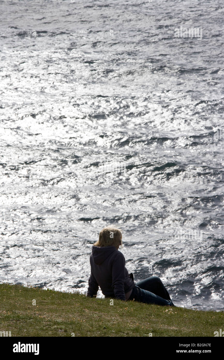 Person sitzt am Rand der Klippe am Loop Head, Atlantikküste, County Clare, Irland Stockfoto
