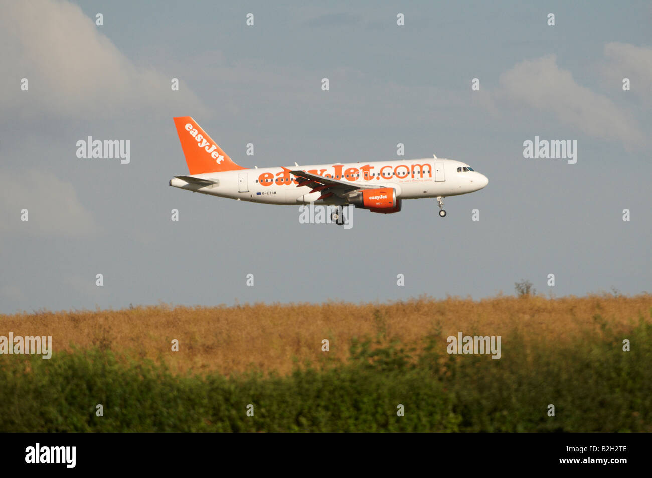 EasyJet Airbus A319 Stansted Dunst Hitzeeinwirkung erscheinen auf einem hügeligen Weizenfeld landen Stockfoto