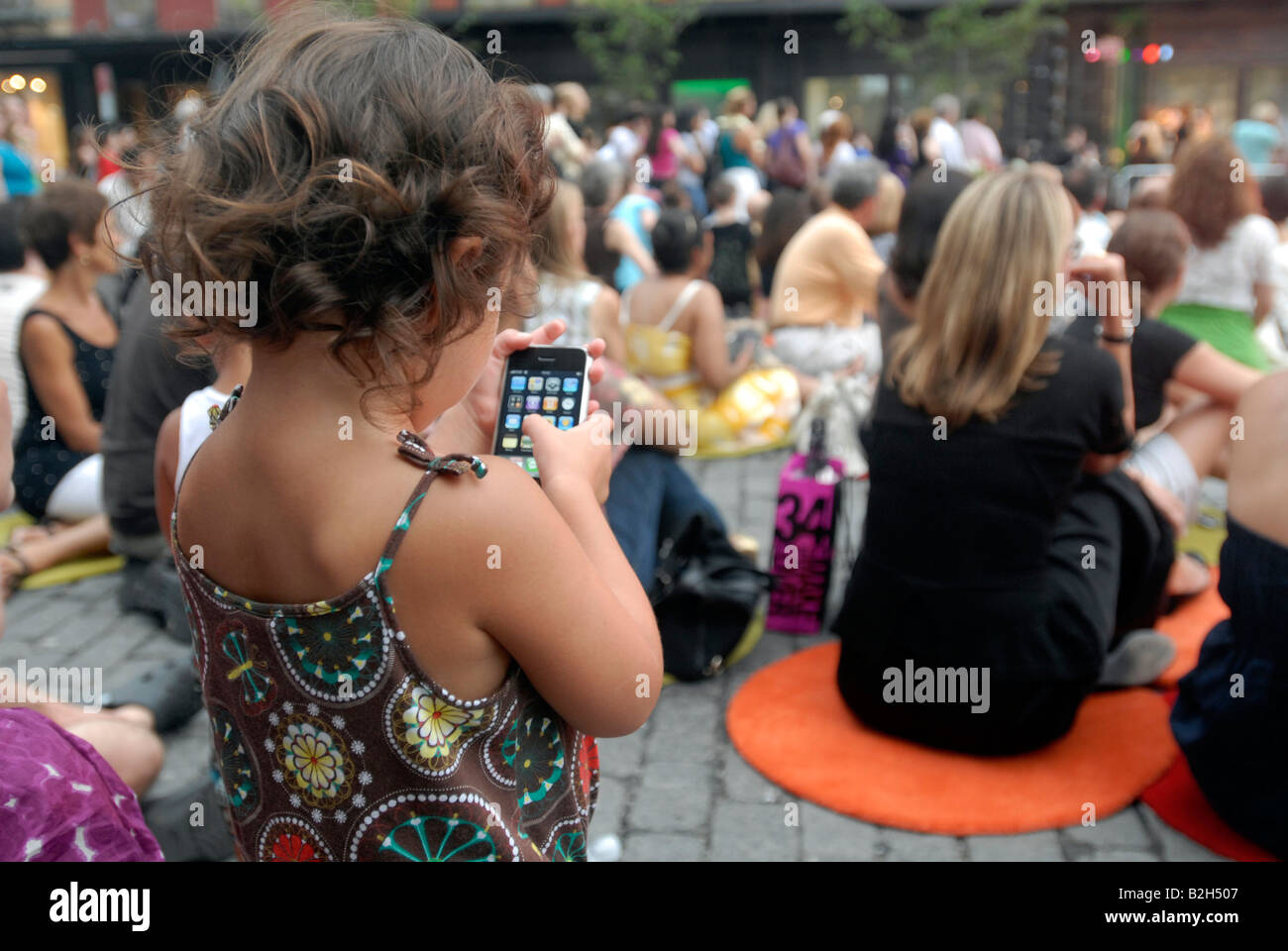 Ein Kind nutzt ihre Eltern iPhone bei einem kostenlosen Konzert in New York Stockfoto