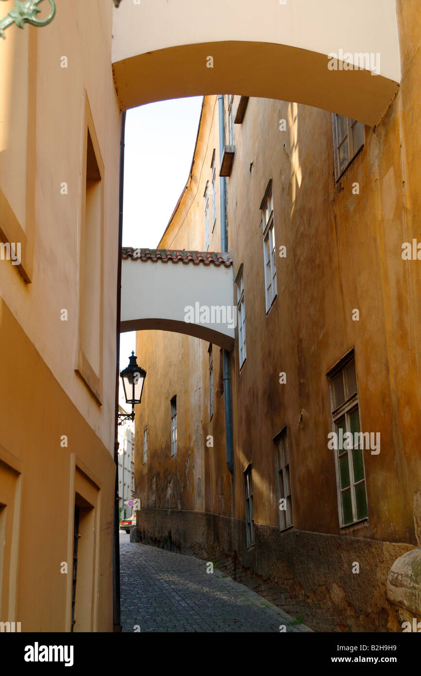 Eine schmale Kopfsteinpflaster Stein Straße in Prag mit rustikalen Gebäuden mit Bögen auf beiden Seiten der Straße verbunden Stockfoto
