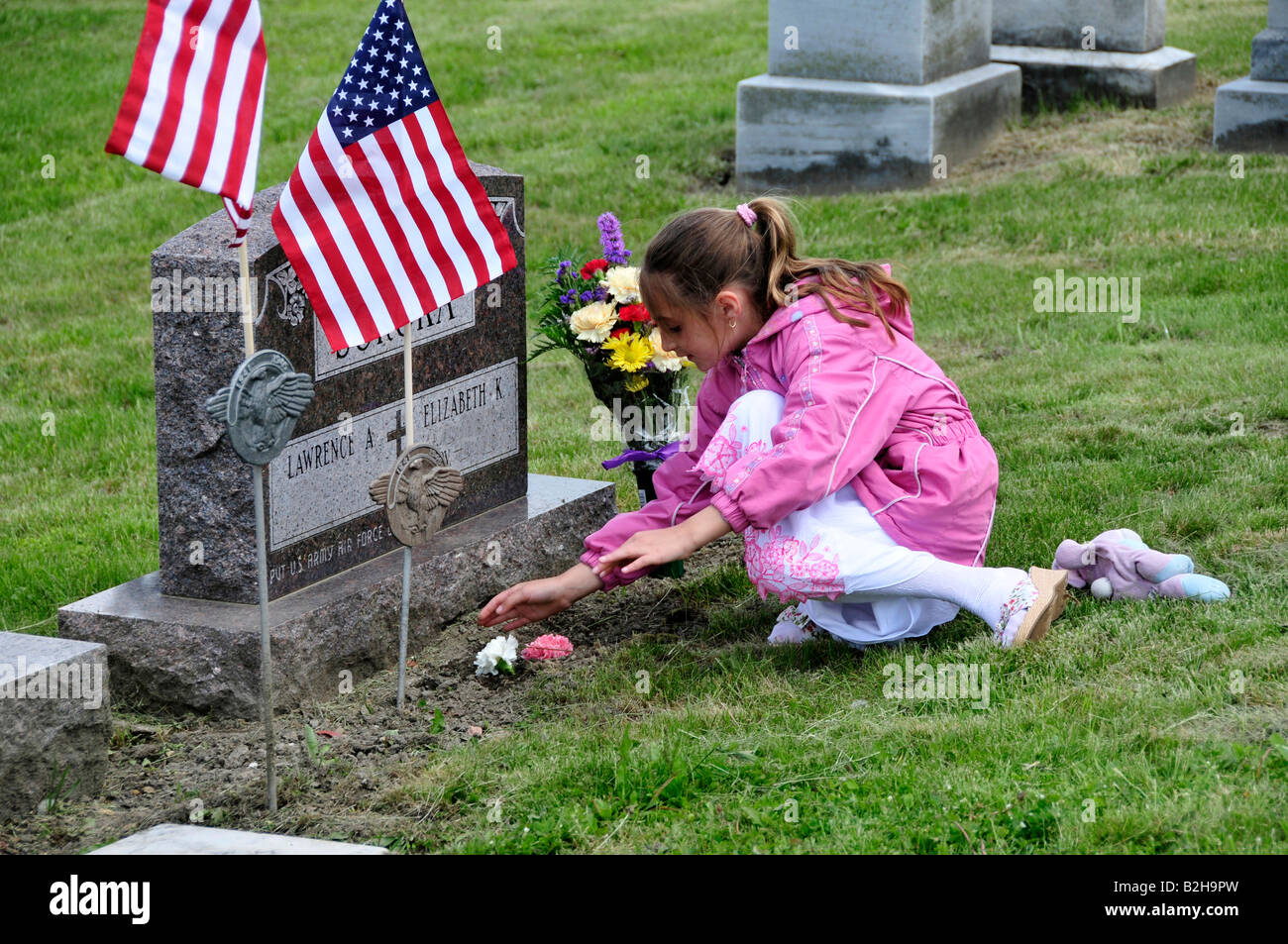 Familie platziert Blumen am Grab Stockfoto