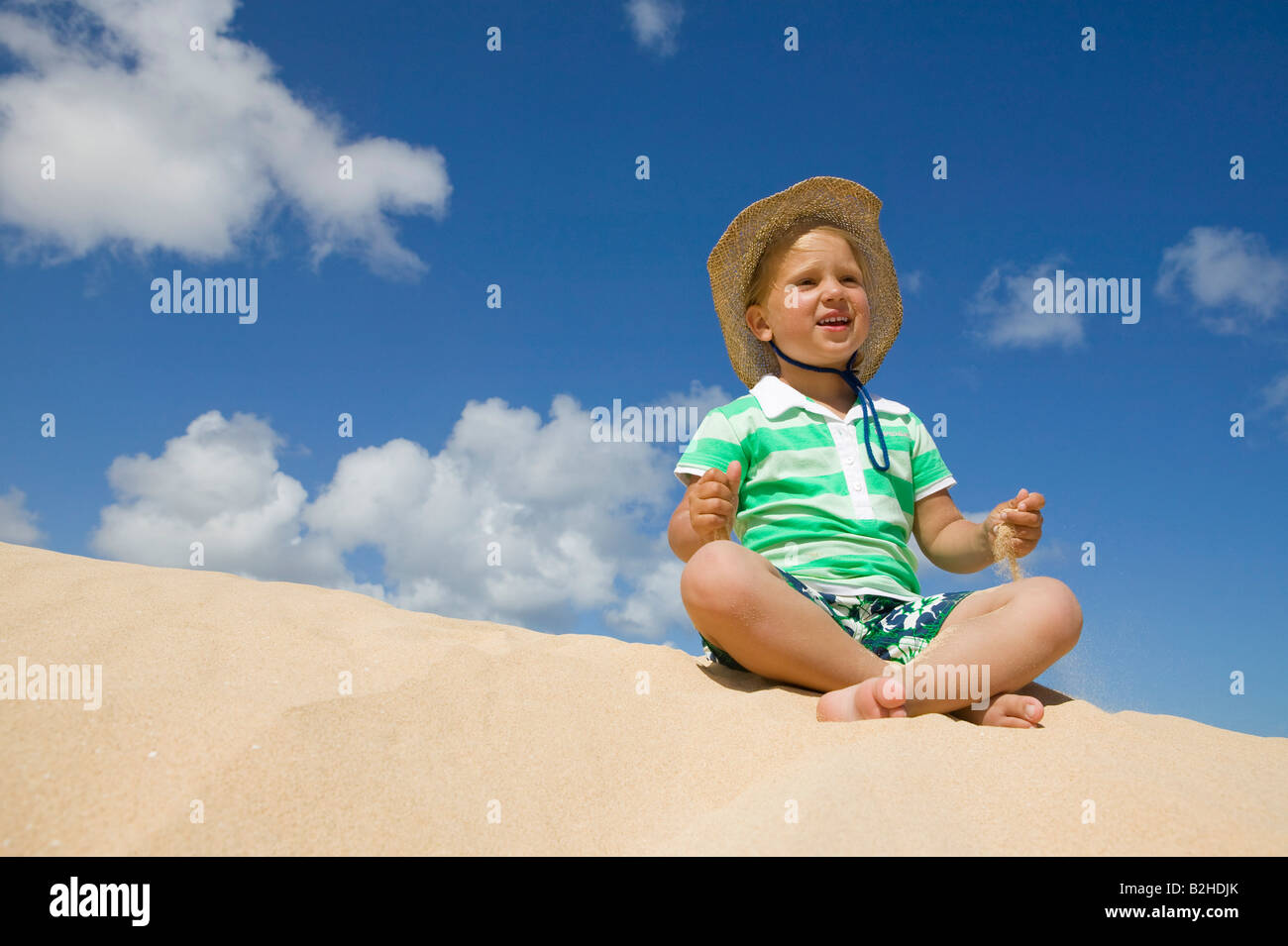 kleines Mädchen sitzt am Sandstrand Stockfoto