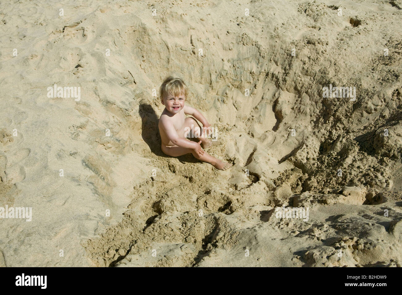 erhöhte Ansicht des kleinen Jungen im Sand Loch sitzen Stockfoto