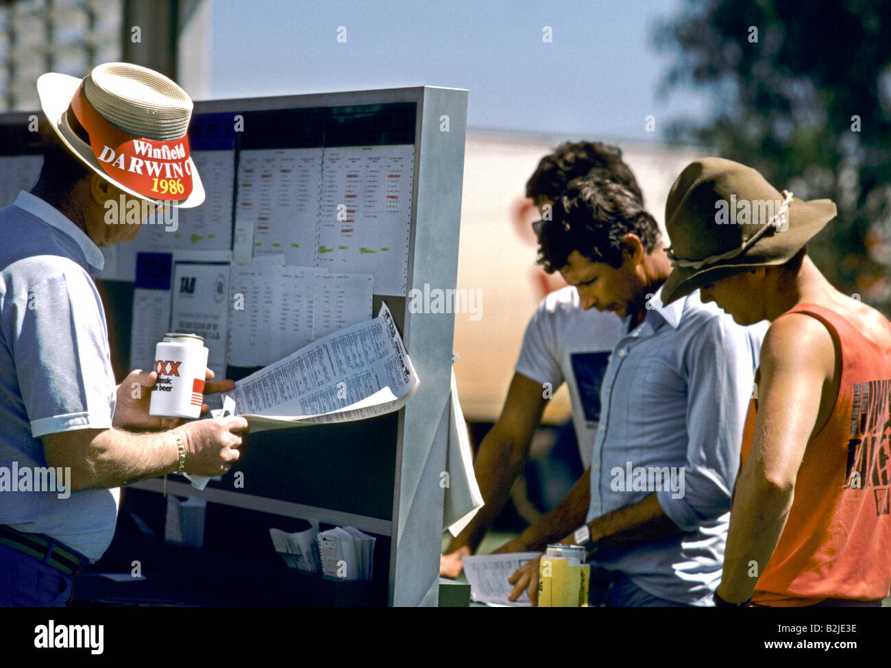 MÄNNER IN KURZEN ÄRMELN STAND AUF EINEM SONNIGEN TAG UND BLICK AUF EIN BRETT- UND KARTENSPIELE RENNEN BEI EINEM PFERDERENNEN Stockfoto