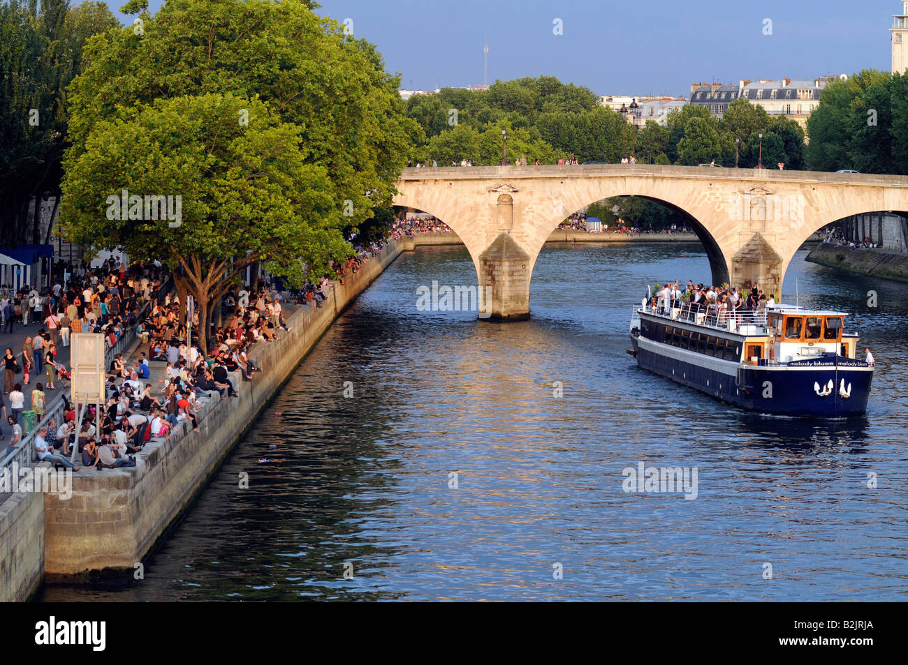 Eine Fliege Boot unter einer Brücke im Zentrum von Paris, während Massen ein Sommerkonzert am Quai der Seine teilnehmen; Frankreich. Stockfoto