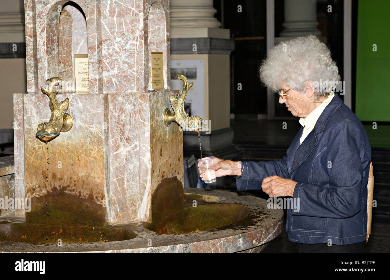 Frau, Füllung Trinkbecher mit Mineralwasser aus der Feder von Pierre le Grande Spa Belgien Stockfoto
