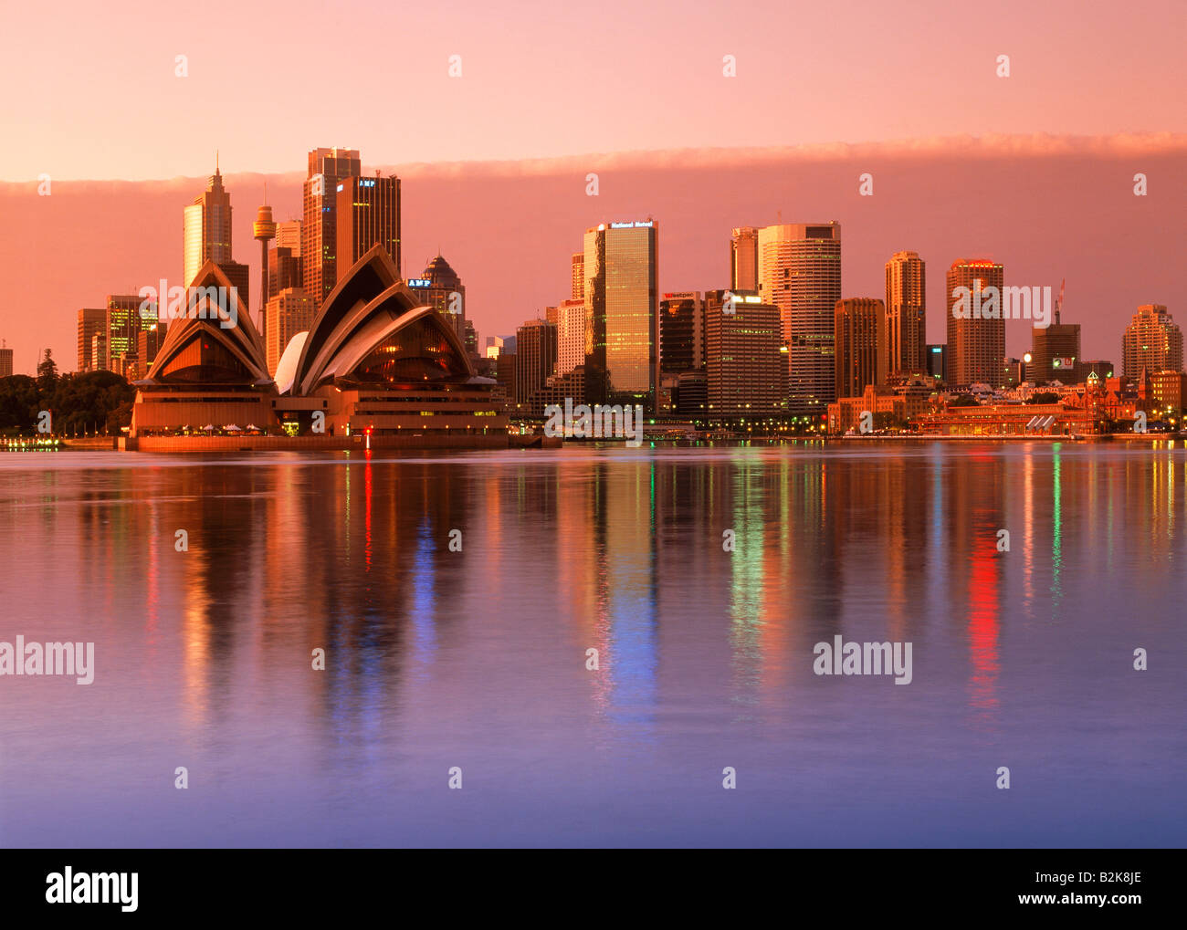 Hellen Sonnenaufgang reflektiert Skyline von Sydney mit Opernhaus reflektierenden über ruhigen Hafen Wasser Stockfoto