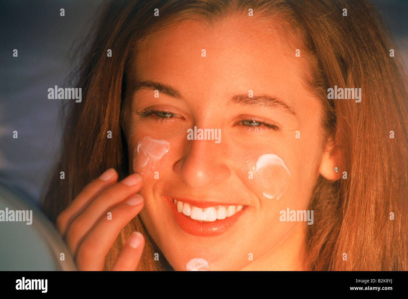 Junge Frau in Spiegel Gesichtscreme auftragen Stockfoto