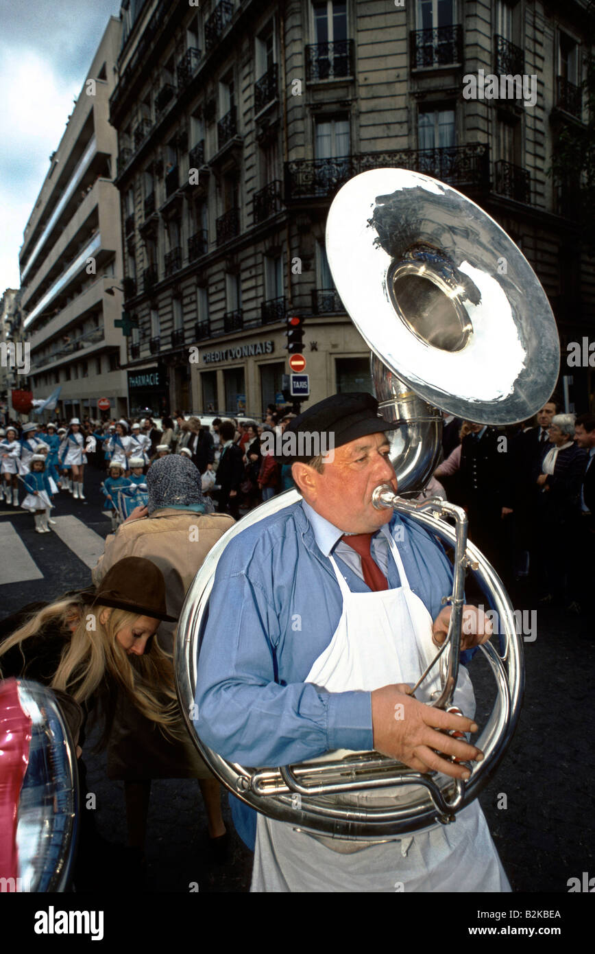 Mann trägt eine weiße Schürze, ein blaues Hemd und eine dunkle rote Krawatte Blaskapelle Instrument zu spielen, in der Straße Paris 1984 Stockfoto