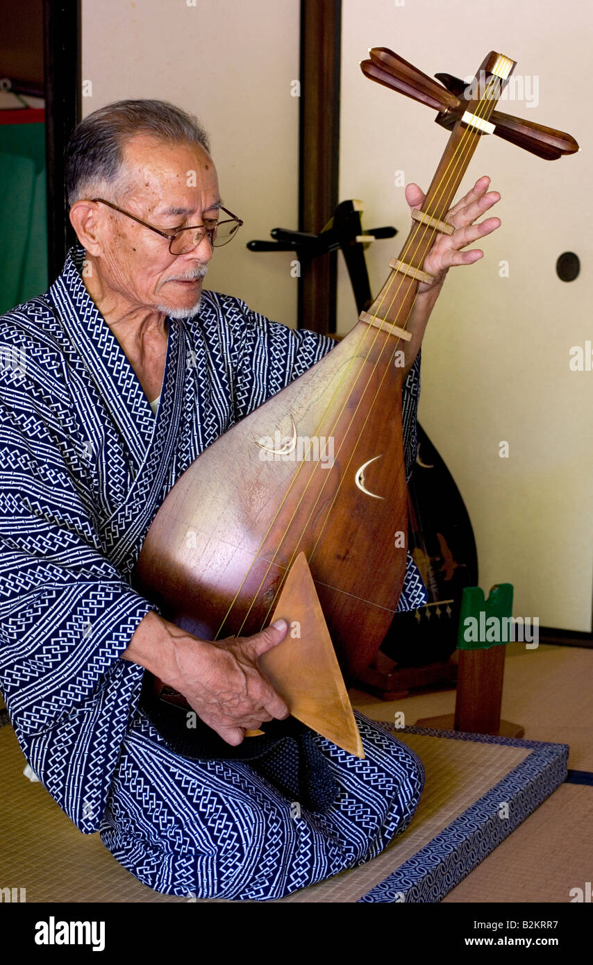 Man spielt einen kurzen necked Bünden laute oder japanischen Biwa Musikinstrument singen und halten eine riesige Auswahl Stockfoto