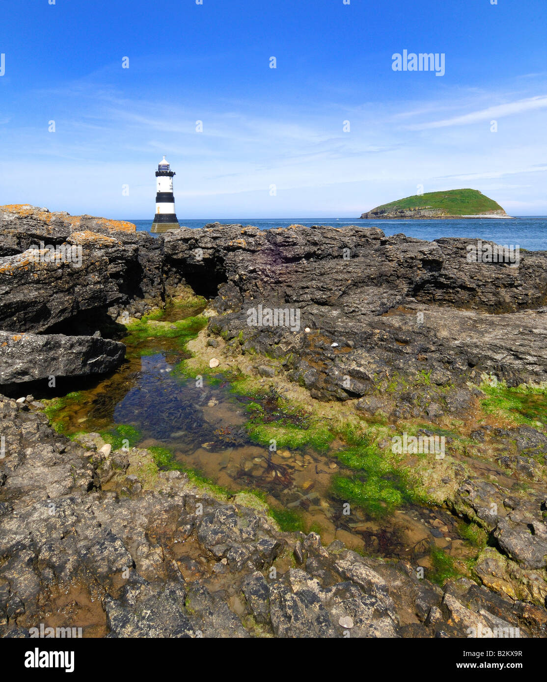 Penmon Point Lighthouse und Puffin Island vor der felsigen und tückischen Küste von Anglesey in Nord-Wales Stockfoto
