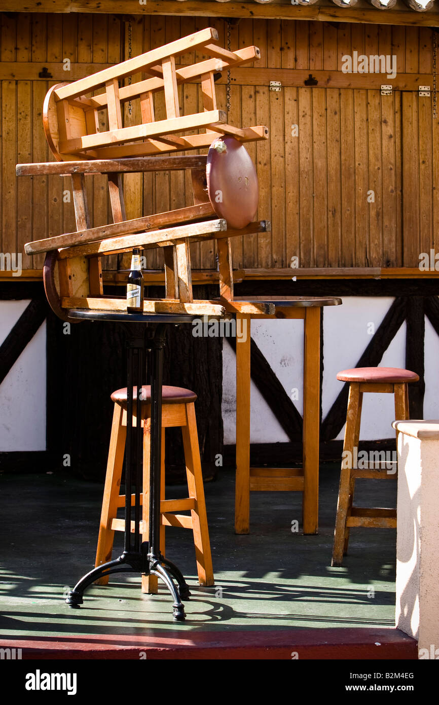 Hölzerne Stühle übereinander gestapelt vor einer geschlossenen Bar in Cala Ratjada, Mallorca, Spanien Stockfoto