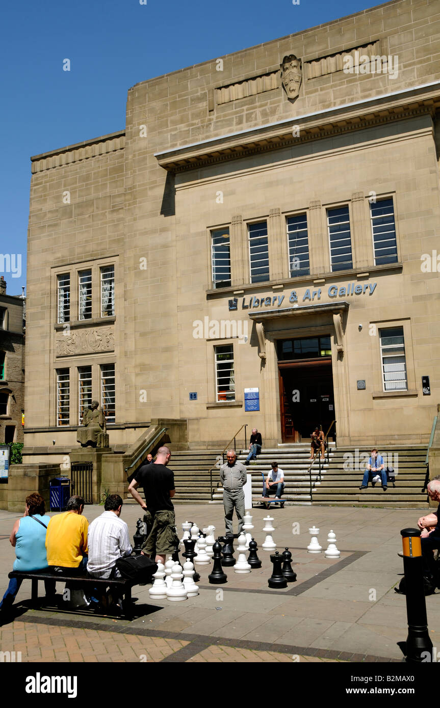 L in Huddersfieldunchtime Shopper und Arbeitnehmer außerhalb der Piazza Einkaufszentrum mit großen Schachfiguren spielen entspannend Stockfoto