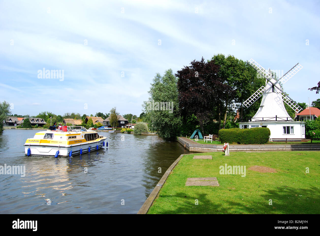 Kreuzfahrt-Boot und hölzerne Windmühle von River Bure, Horning, Norfolk Broads, Norfolk, England, Vereinigtes Königreich Stockfoto