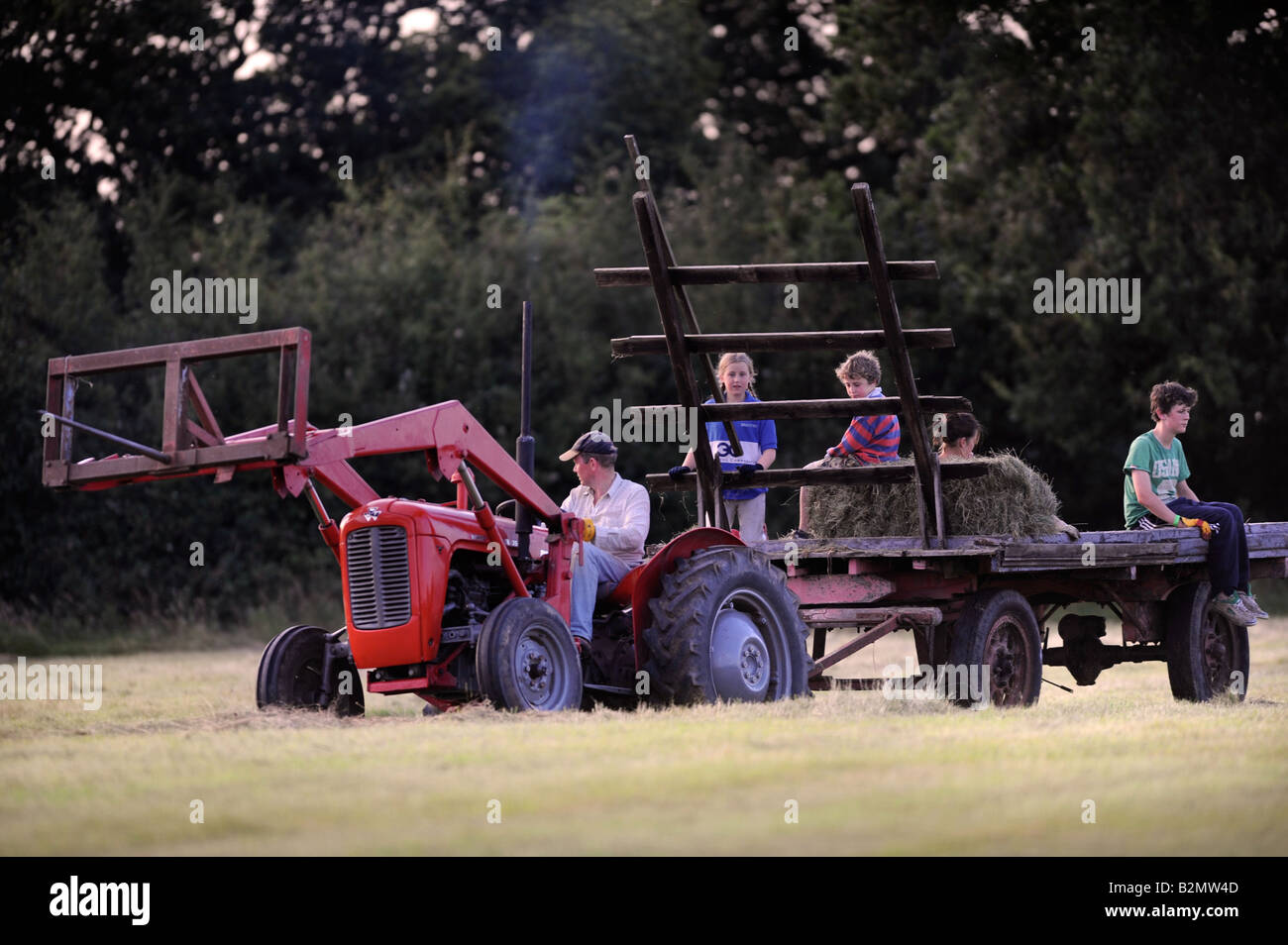 EINE BAUERNFAMILIE SAMMELN HEU IM TRADITIONELLEN STIL IN GLOUCESTERSHIRE UK Stockfoto