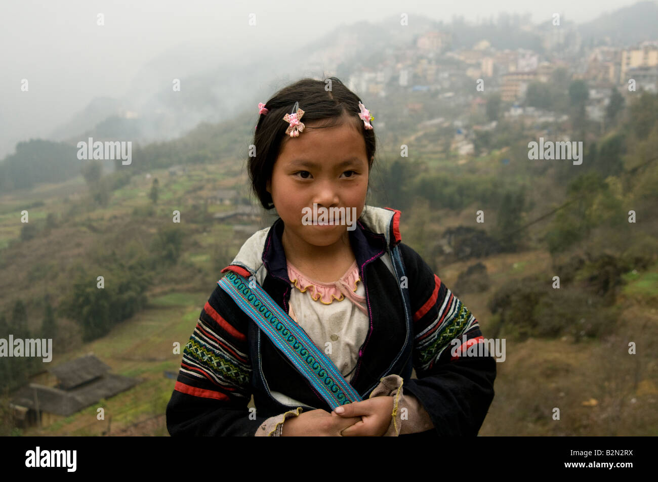 Eine junge Black Hmong tribal Mädchen mit den nebligen Hügeln rund um Sapa Vietnam hinter ihr Stockfoto