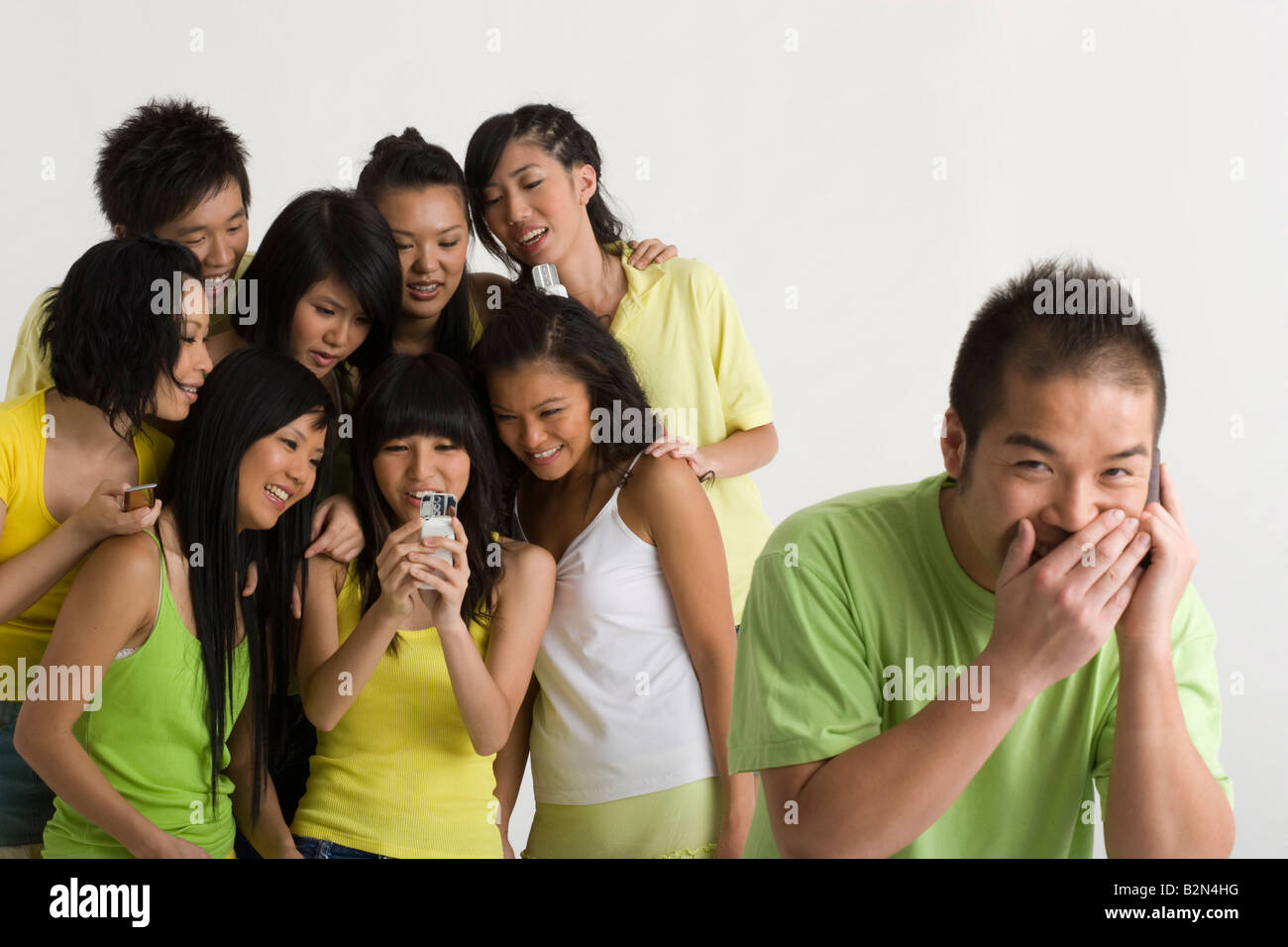 Nahaufnahme eines jungen Mannes, das Gespräch auf ein Mobiltelefon mit einer Gruppe seiner Freunde hinter ihm stehen und Lächeln Stockfoto