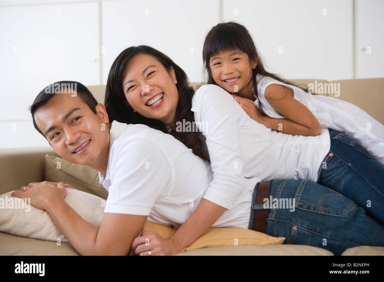 Nahaufnahme einer Mitte Erwachsene Frau mit ihrer Tochter liegen auf einer Mitte erwachsenen Mannes, Singapur Stockfoto