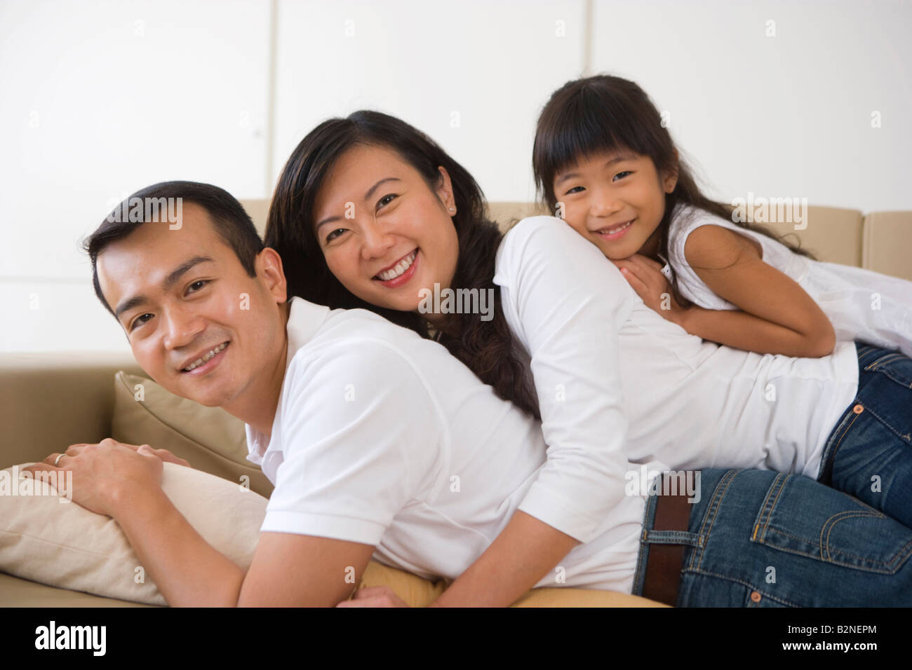 Porträt einer Mitte Erwachsene Frau mit ihrer Tochter liegen auf einer Mitte erwachsenen Mannes, Singapur Stockfoto
