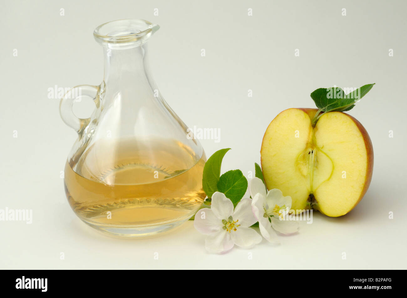 Heimischen Apfel (Malus Domestica). Halbierte Früchte, Blüten und einem Dekanter Apfelessig Stockfoto