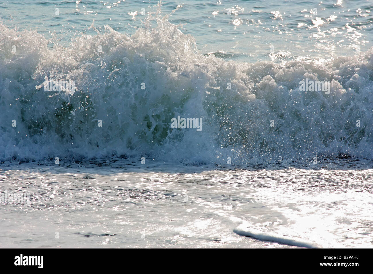 Eine Hintergrundbeleuchtung Wellen am Ufer brechen Stockfoto