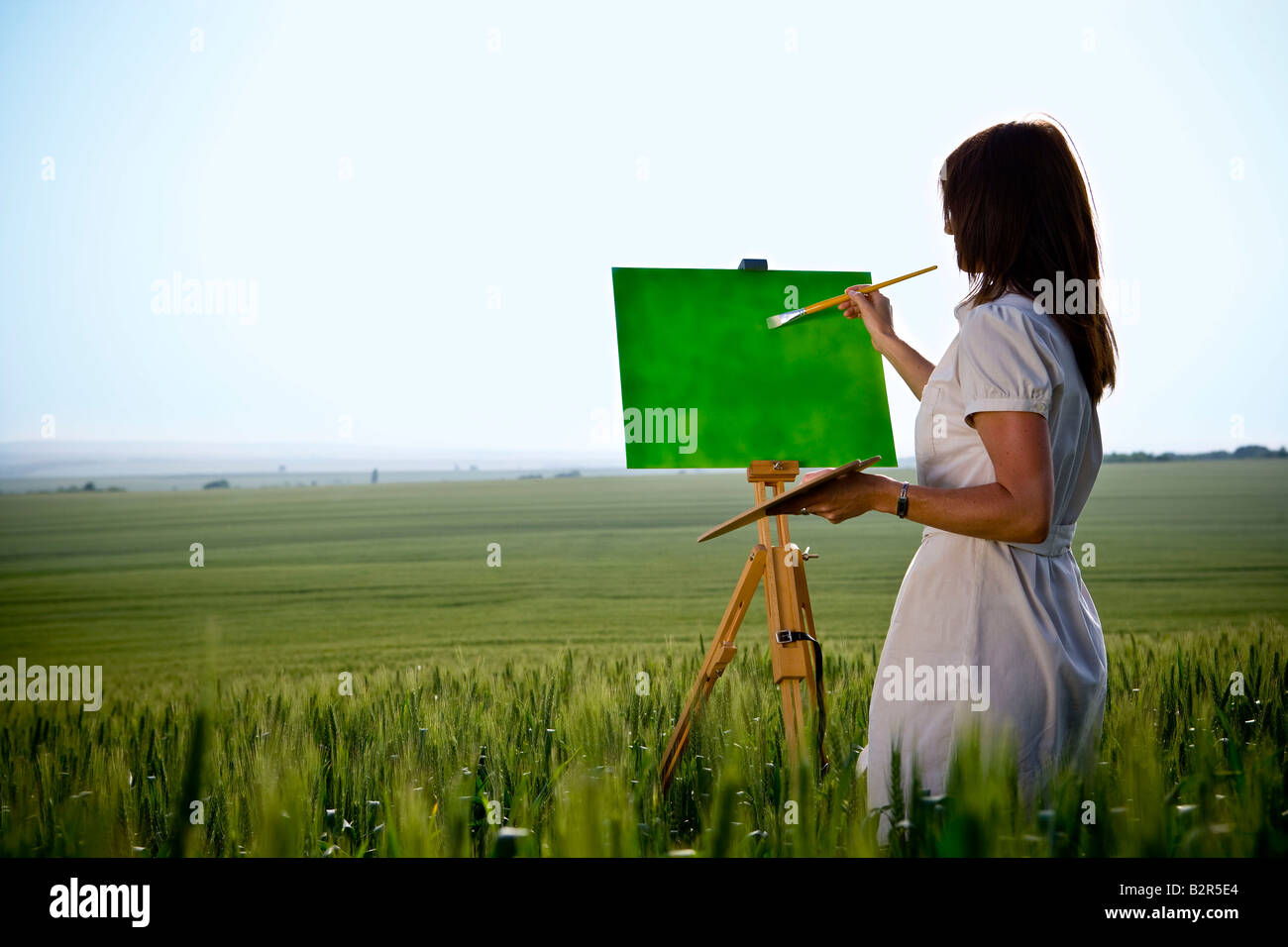Frau malt im Weizenfeld, hinten Stockfoto