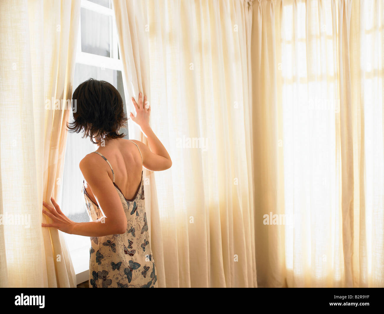 Frau, die durch Fenster Stockfoto