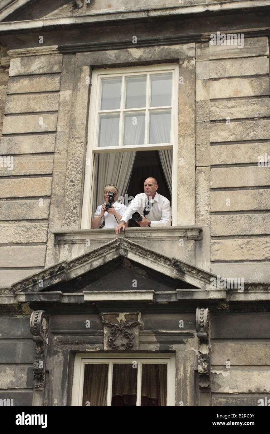 Zwei Fotografen lehnt sich aus dem Fenster in Vorbereitung für eine Hochzeit zu fotografieren Stockfoto