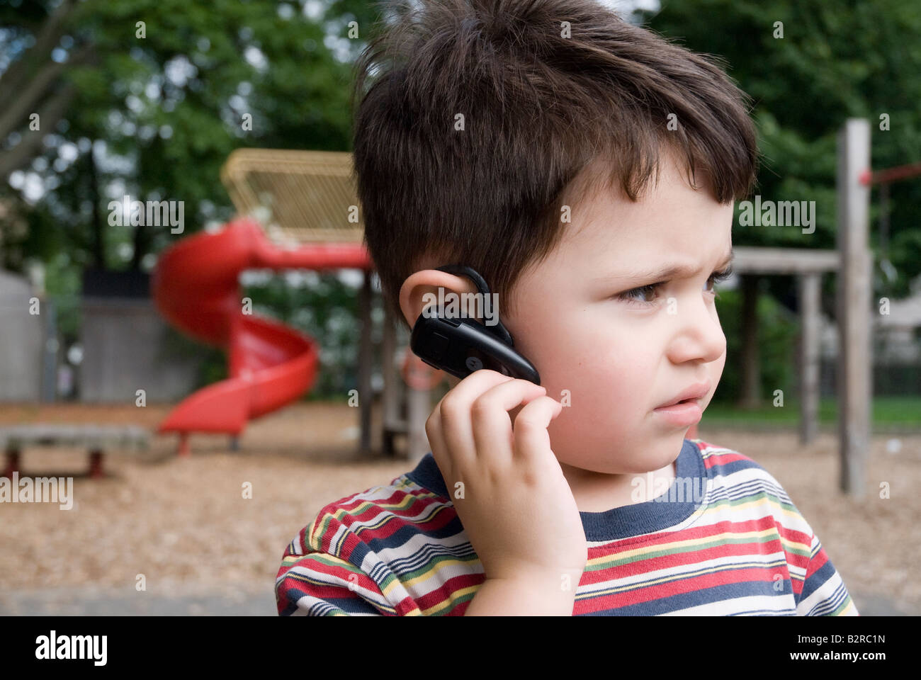 Drei Jahre alte junge Gespräche über Handy mit einem Bluetooth-Kopfhörer Stockfoto