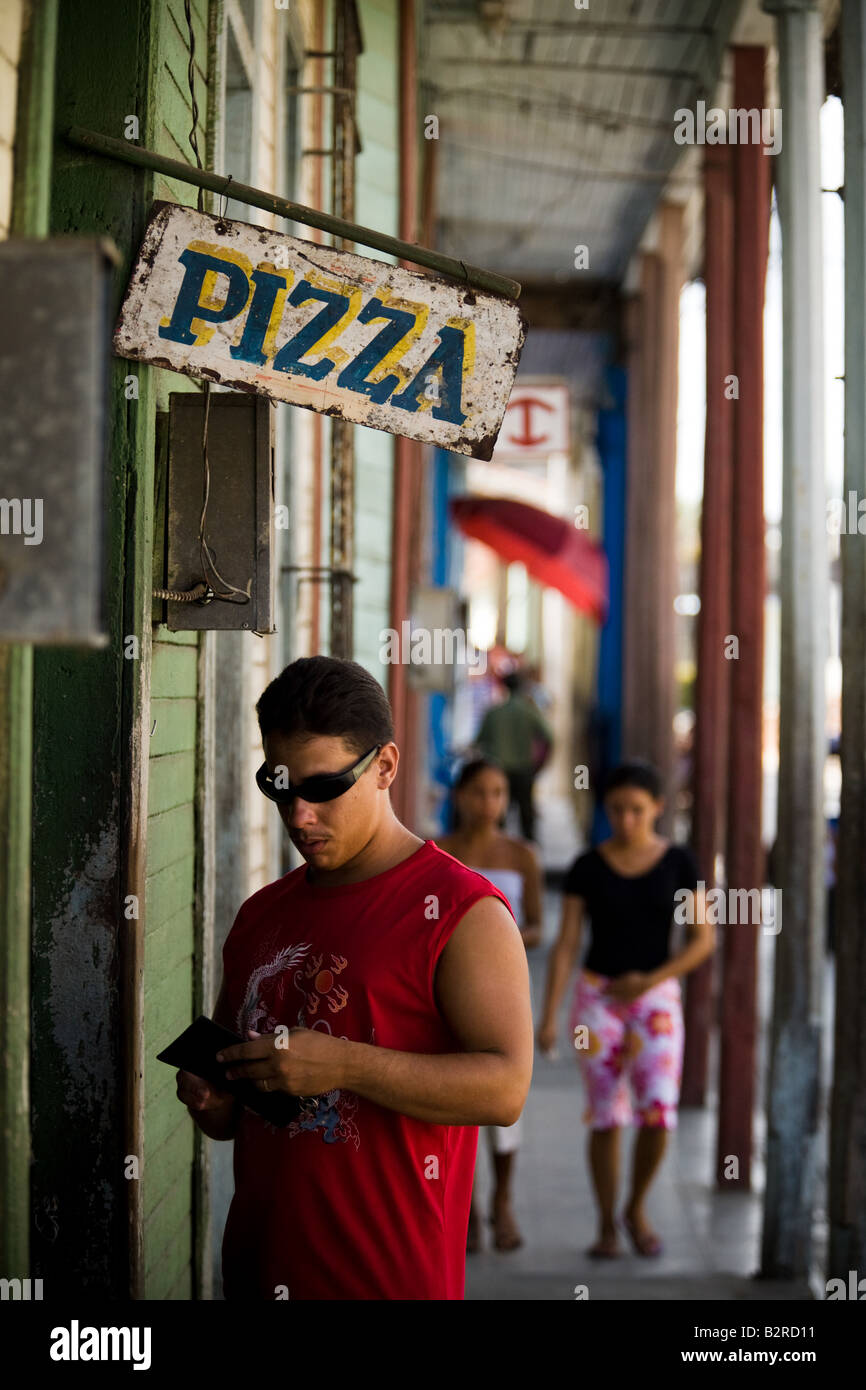 Ein Mann durch seine Brieftasche mischt, als er bereitet sich für Pizza auf der Straße von Baracoa, Kuba zu bezahlen Stockfoto