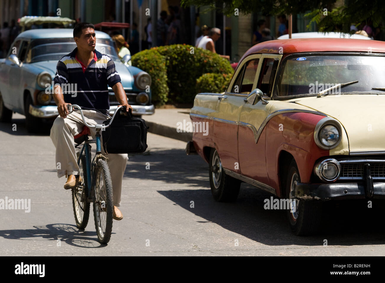 Ein Mann reitet sein Fahrrad er im Laufe der alten amerikanischen Autos auf der Straße von Baracoa, Kuba Stockfoto