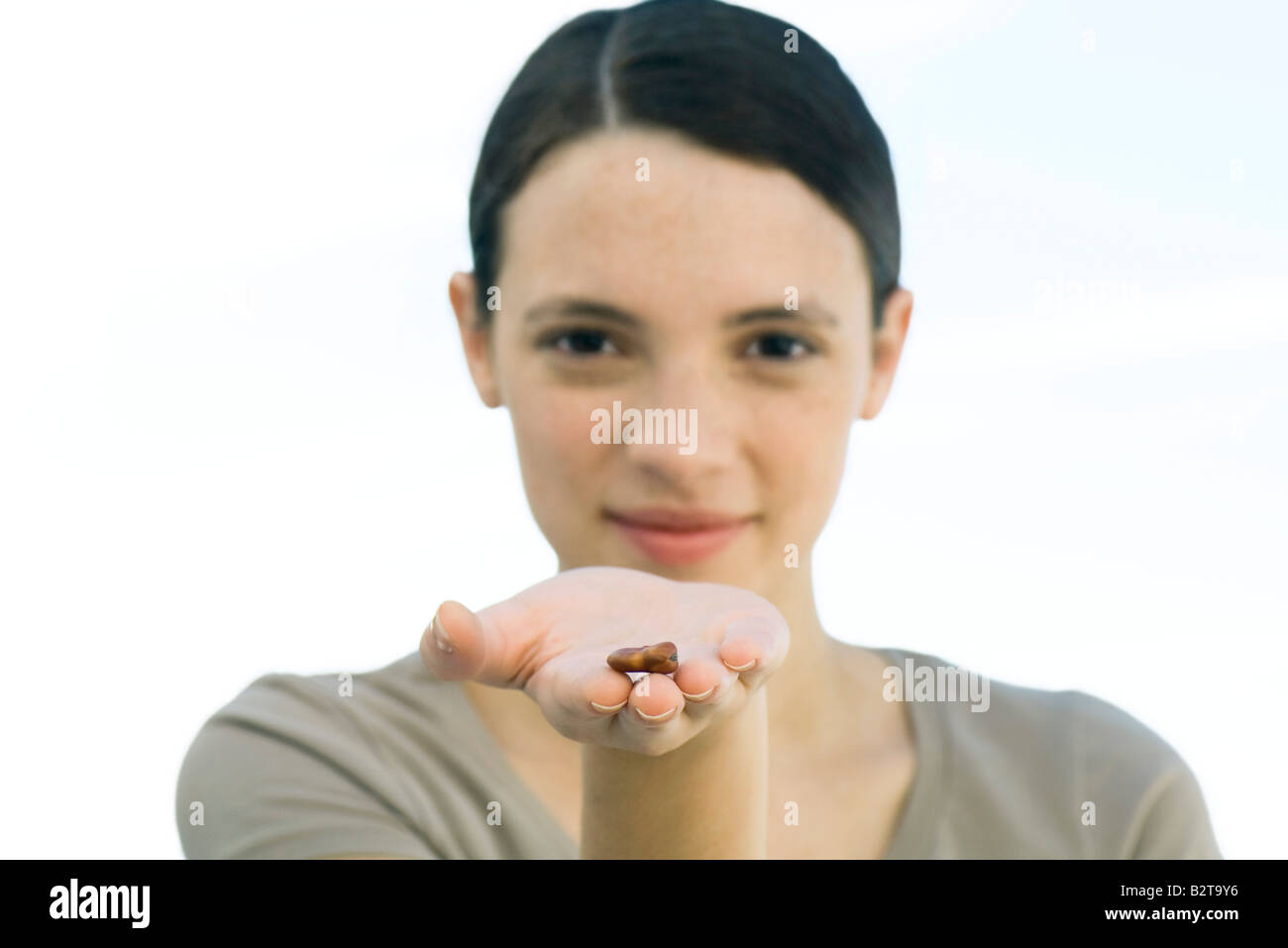 Junge Frau hält sich getrocknete Bohnen in Handfläche Stockfoto