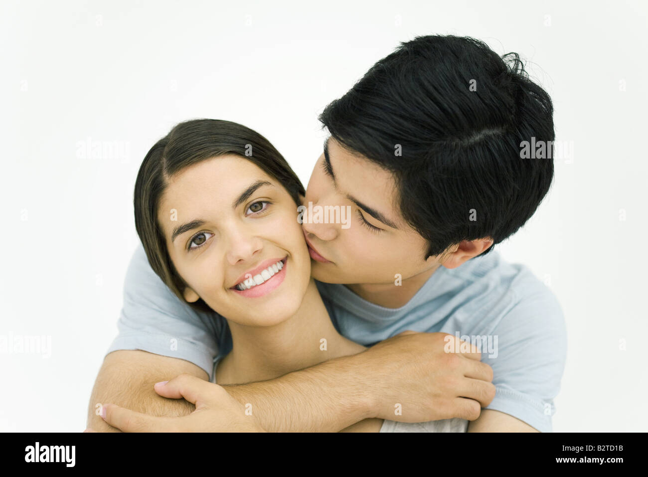 Junger Mann, die Frau auf die Wange, in die Kamera lächelnde Frau küssen Stockfoto