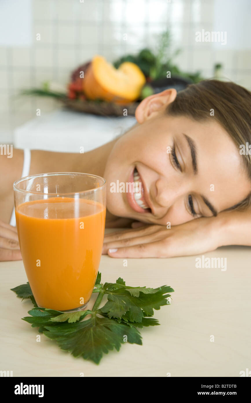 Lächelnde Frau ruhenden Kopf auf Theke, Blick auf Glas Gemüsesaft, Stockfoto