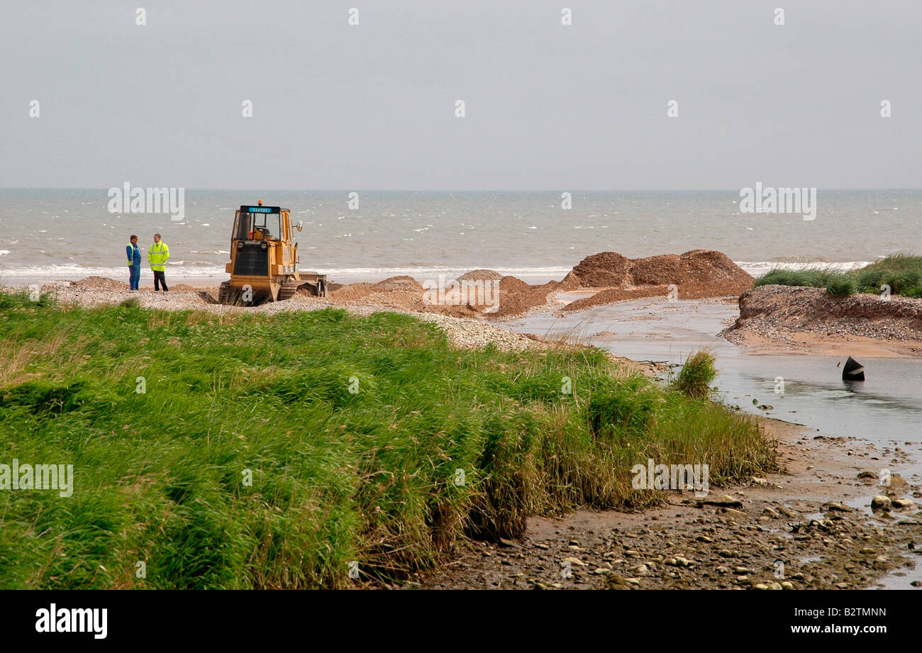Eine Raupe/Bagger bei der Arbeit - Entwässerung am Strand für einen blockierten Fluss und anschließende Land Flut zu schaffen. Stockfoto