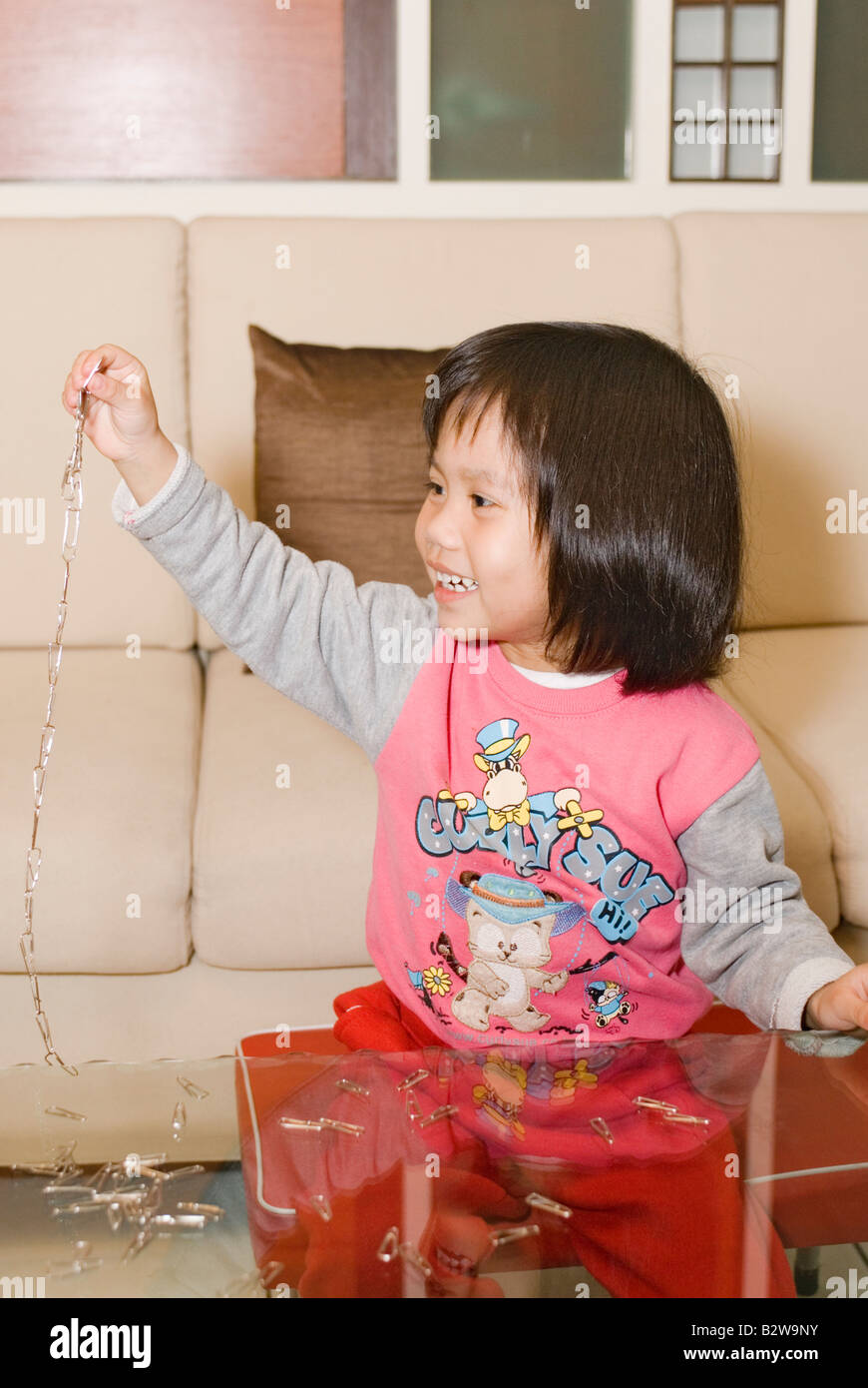 4 jährige asiatische Mädchen spielen mit Büroklammer Kette Stockfoto