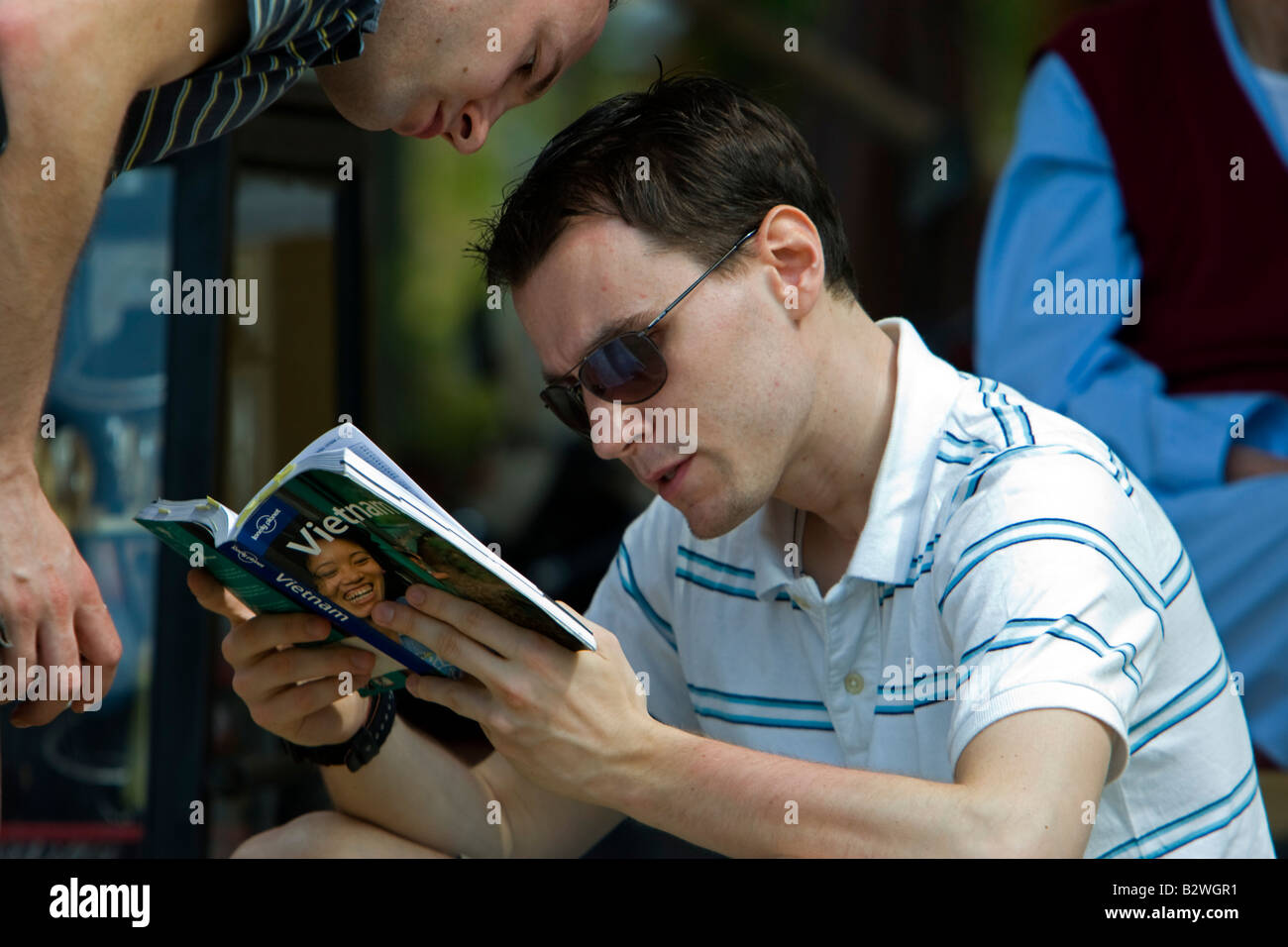 Junge Männer konsultieren Reiseführer Lonely Planet Vietnam Hoi An Vietnam Stockfoto