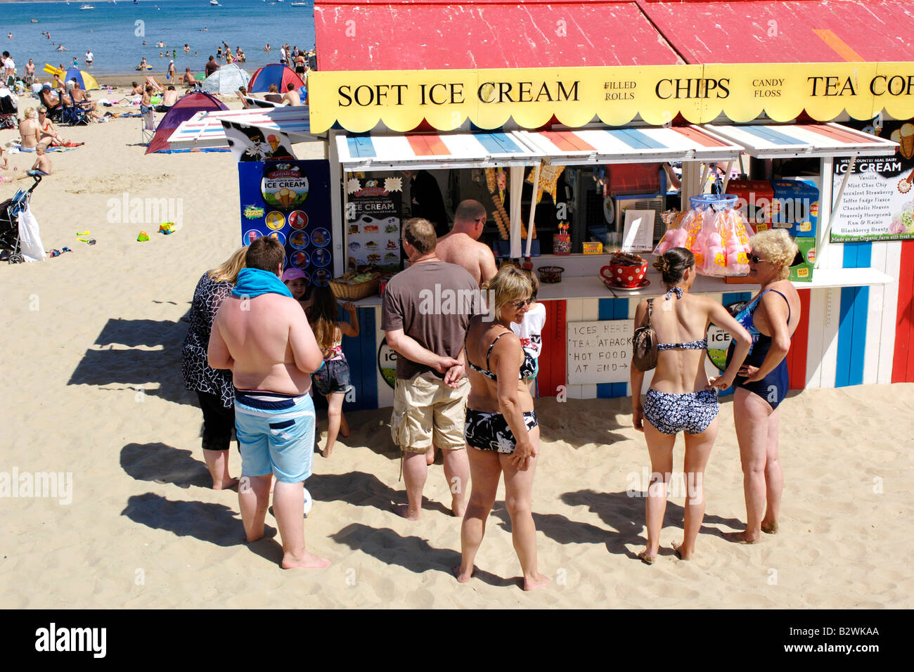 Menschen Schlange, um weiche Eis an einem heißen Tag am Strand von Weymouth zu kaufen Stockfoto