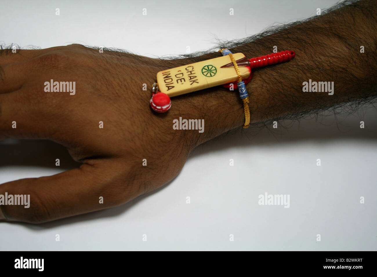 Cricket-Schläger und Ball zu einem Inder Hand auf beliebte indische Festival Raksha India gebunden Stockfoto