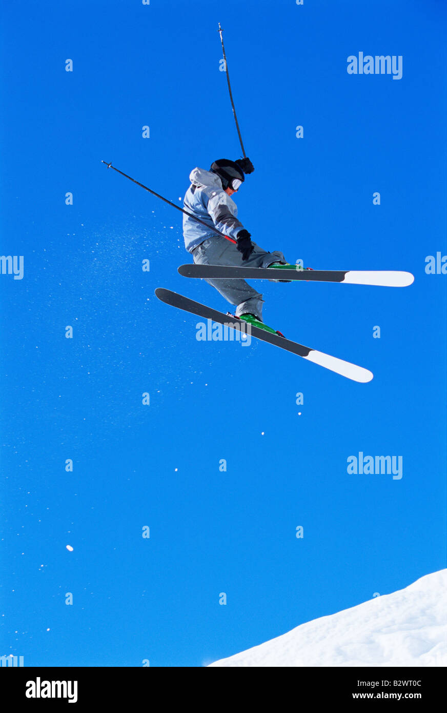 Skifahrer, die dabei auf verschneiten Hügel springen Stockfoto
