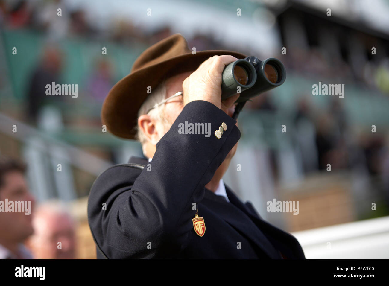 HERR IN TRILBY HUT EIN PFERDERENNEN MIT DEM FERNGLAS BEOBACHTEN Stockfoto