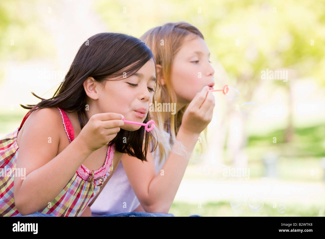 Zwei junge Mädchen bläst Seifenblasen im freien Stockfoto