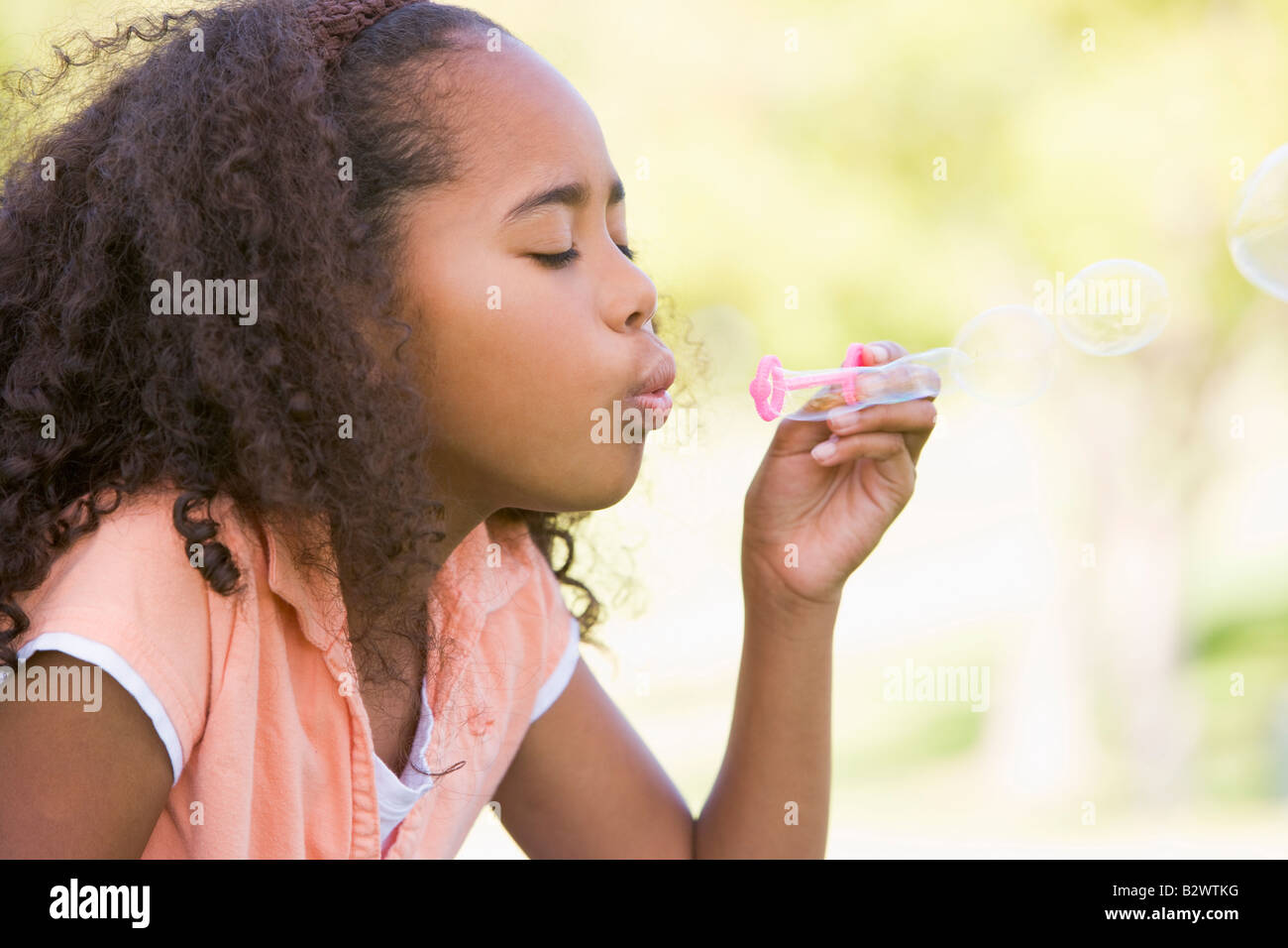 Junge Mädchen bläst Seifenblasen im Freien Stockfoto