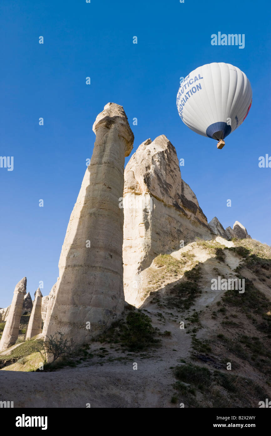 Heißluft-Ballon über die phallischen Säulen bekannt als Feenkamine im Tal bekannt als Liebe Tal in der Nähe von Göreme, Cappadocia Stockfoto