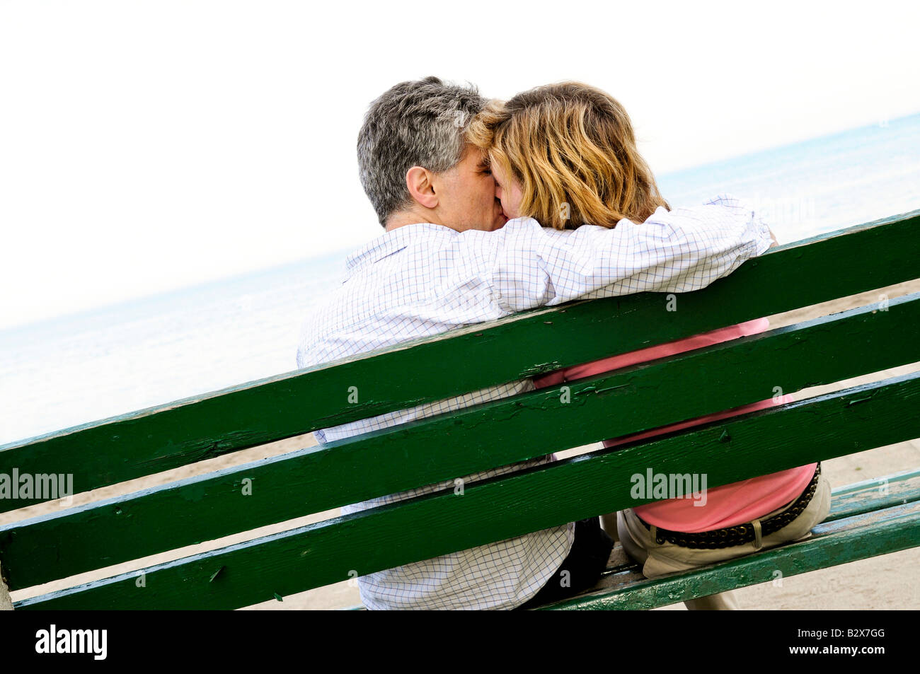 Reife romantisches Paar auf einer Bank am Meeresstrand Stockfoto