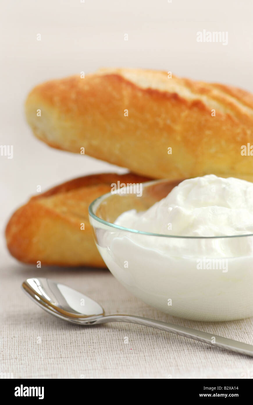 Joghurt in einer klaren Glasschale und Brot serviert Stockfoto