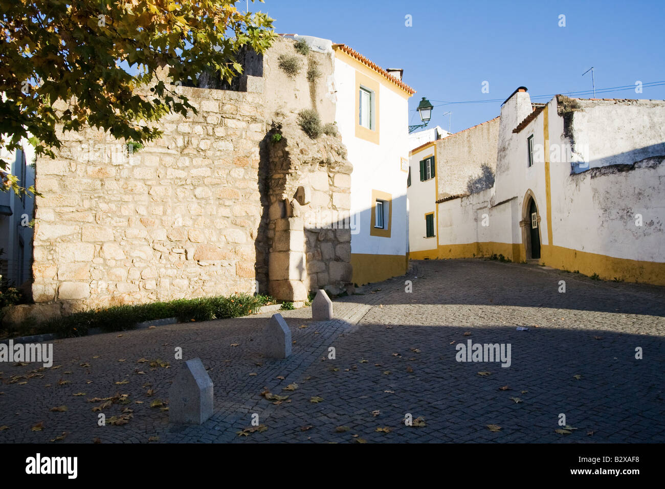 Straße von Crato mit Blick auf die alte Schlossmauer, die von den alten Häusern verwendet. Crato, Portalegre, Alentejo, Portugal. Stockfoto