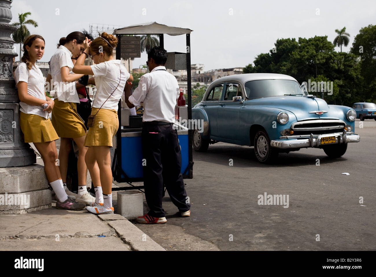 Teenage-Mädchen in Schuluniformen kaufen kalte Leckereien gemacht von zerstoßenem Eis und süßen Sirup in Havanna, Kuba Stockfoto
