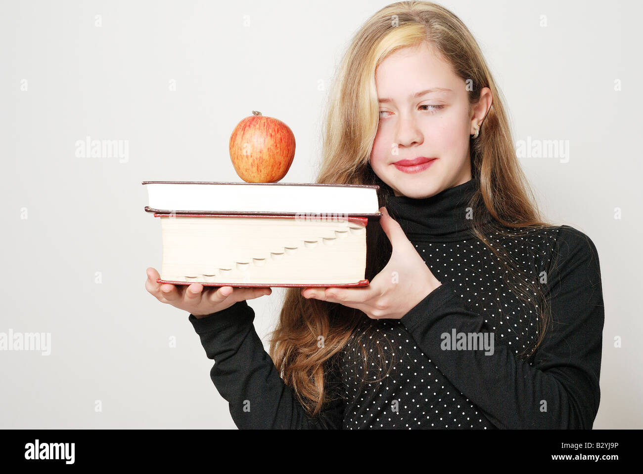 Das Schulmädchen mit Büchern und einen Apfel Stockfoto